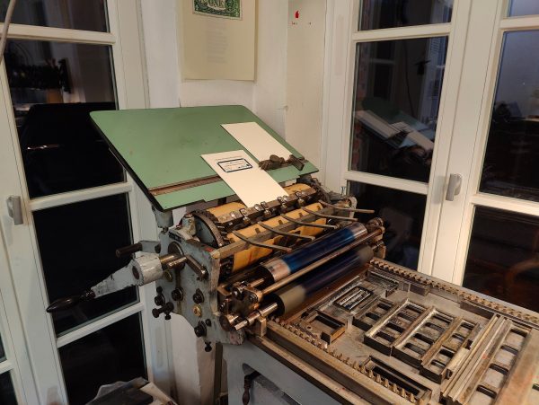 Foto der Druckmaschine, einer manuellen Zylinderandruckpresse Korrex Modell Stuttgart Typ II, Baujahr 1964. Dies war die kleinste auflagenfähige Maschine der Firma Max Simmel und war in ihrer Zeit in beinahe jeder ernstzunehmenden Druckerei und Hochschule für Kleinbedarf und Korrekturbögen zu finden.