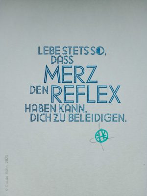 Foto einer Karte im Blei-Handsatz. Der Text der blau gedruckten Schrift lautet: Lebe stets so, dass Merz den Reflex haben kann, Dich zu beleidigen.