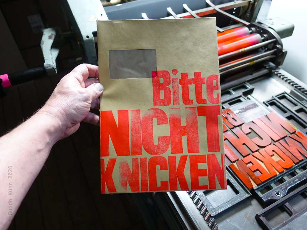 Foto mit C4 Umschlag, der blockartig mit dem Text BITTE NICHT KNICKEN bedruckt ist