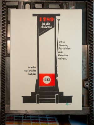 Foto des fertigen Druckes. Zu sehen ist eine schwarze Silhouette einer Guillotine mit der rot hinterdruckten Jahreszahl 1728 in der alten Antiqua Normande, darunter invers in der Signal der Teilsatz "ist die Antwort" seitlich rechts steht die Fortsetzung "wenn Bonzen, Faschisten und Konzerne meinen," darunter seitlich links der Guillotine "es wäre mal wieder Zeit für" und im im roten Kopfschild die Jahreszahl 1933 in der Tannenberg Fraktur als Abschluss des Satzes.